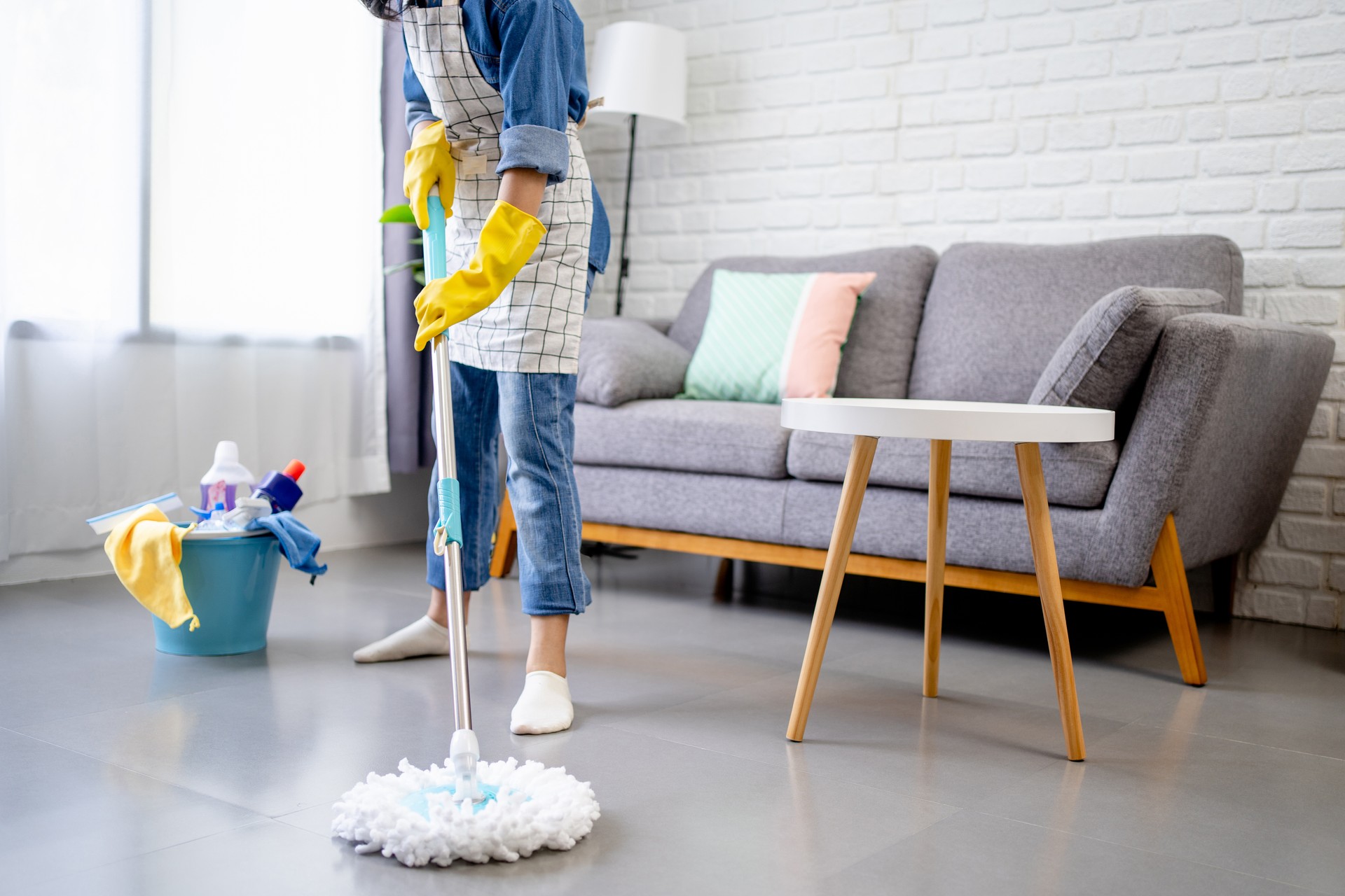 Young woman holding a floor wiper and wiping floor, keeping the daily home hygiene and doing housework.